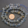 String of blue beads with a penny for scale on a gray background