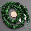 Green beaded necklace with a coin for scale on a gray background