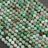 Close-up of faceted round Chrysoprase beads in varying shades of green, with natural brown and white matrix inclusions.
