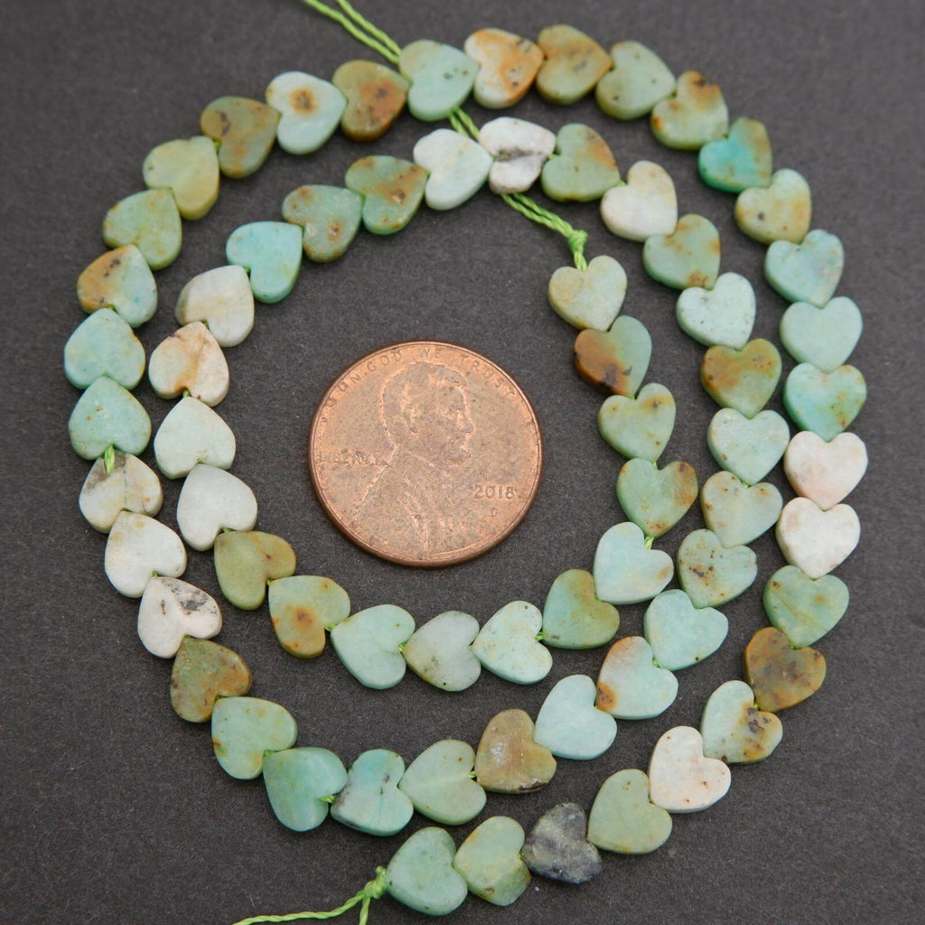 String of heart-shaped beads with a penny for scale on a dark surface