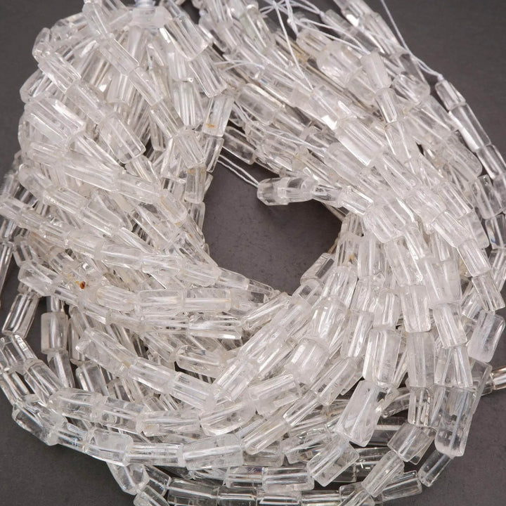 Clear glass beads on a string with a penny for scale on a dark background