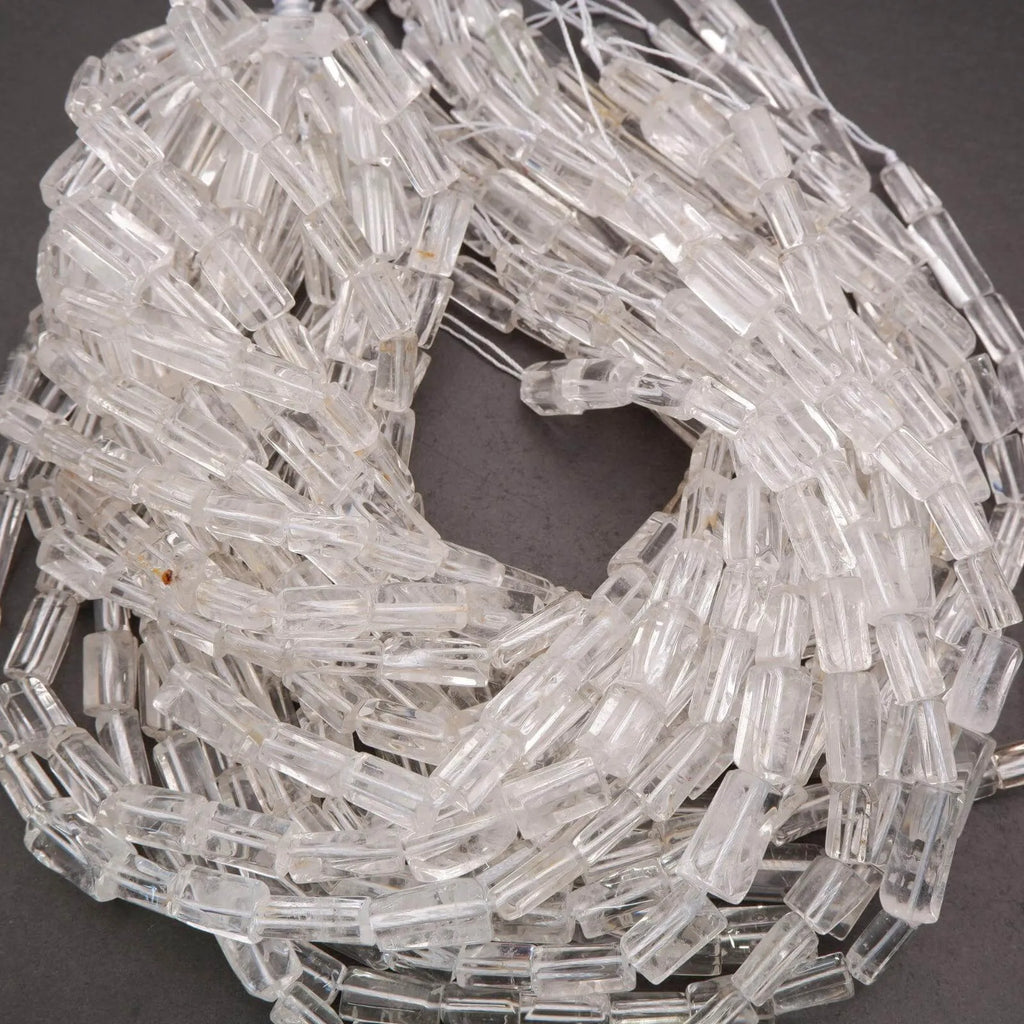 Clear glass beads on a string with a penny for scale on a dark background