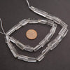 Clear glass beads on a string with a penny for scale on a dark background