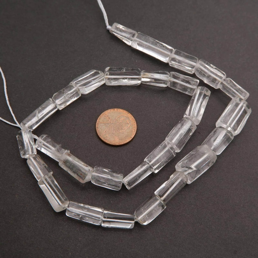 Clear glass beads on a string with a penny for scale on a dark background
