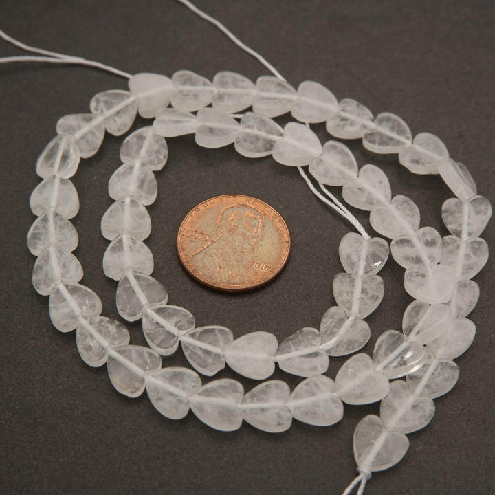 String of clear beads with a penny for scale on a dark surface