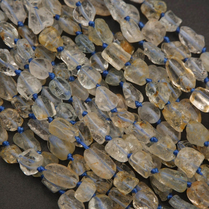 String of clear and amber beads with blue thread on a dark background