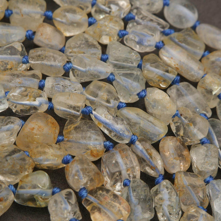 Close-up of amber-colored beads with blue strings on a dark background