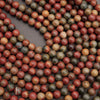 Close-up of marbled beads in red, brown, and beige on a dark surface
