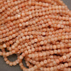 Close-up of a pile of small peach-colored beads on a gray background