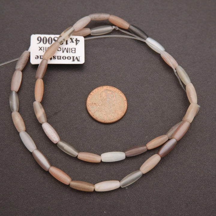 Necklace with oval beads on a dark surface, next to a coin for scale.