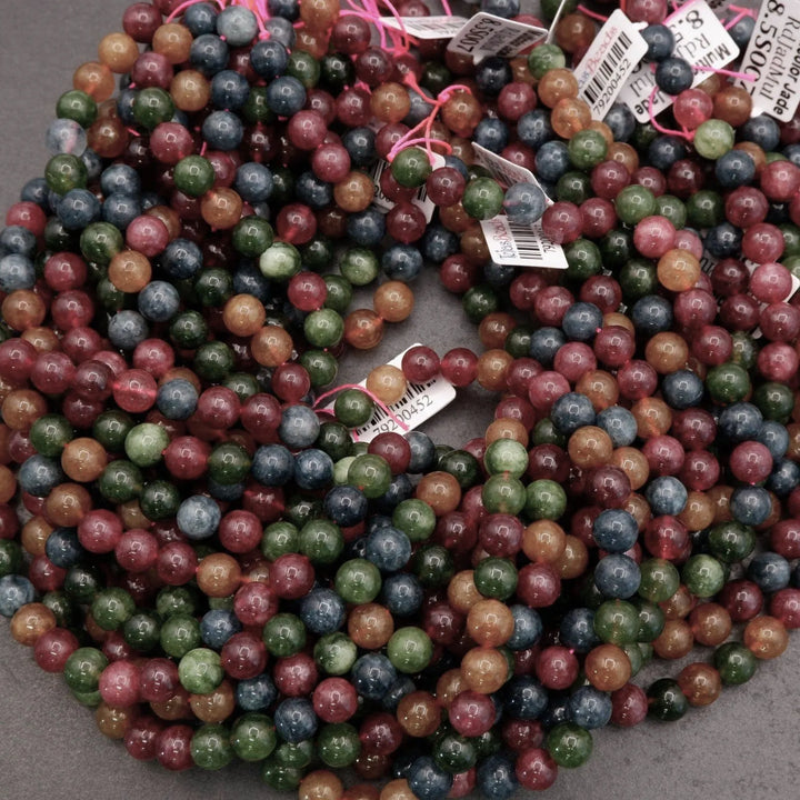 Multicolor Jade beads feature a vibrant mix of reds, greens, ambers, and blues with natural variation throughout each strand.