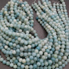 Two strands of light blue and green beads on a dark surface