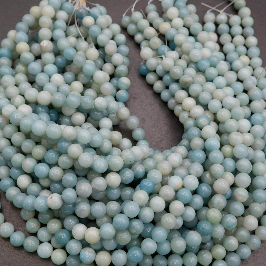 Two strands of light blue and green beads on a dark surface