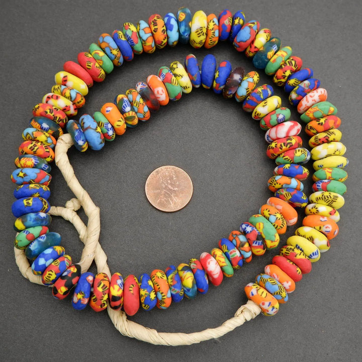 Colorful beaded necklace on a dark surface with a penny for scale.