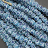 Close-up of blue beads with floral patterns on a gray background
