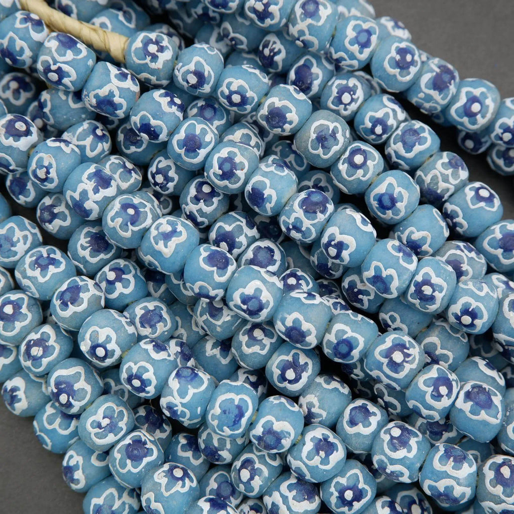 Close-up of blue beads with floral patterns on a gray background