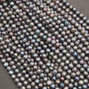 Strands of peacock freshwater pearls laid in diagonal rows on a gray background, with blue and purple luster