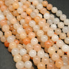 Peach Aventurine Beads showing a mix of hues from light to dark peach, with an almost orange appearance.
