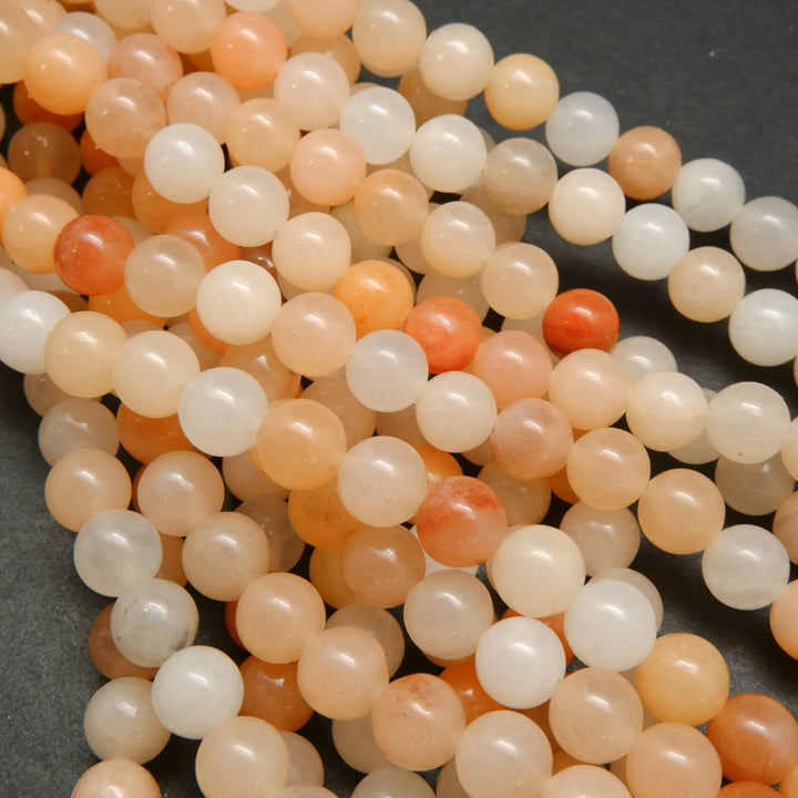 Peach Aventurine Beads showing a mix of hues from light to dark peach, with an almost orange appearance.