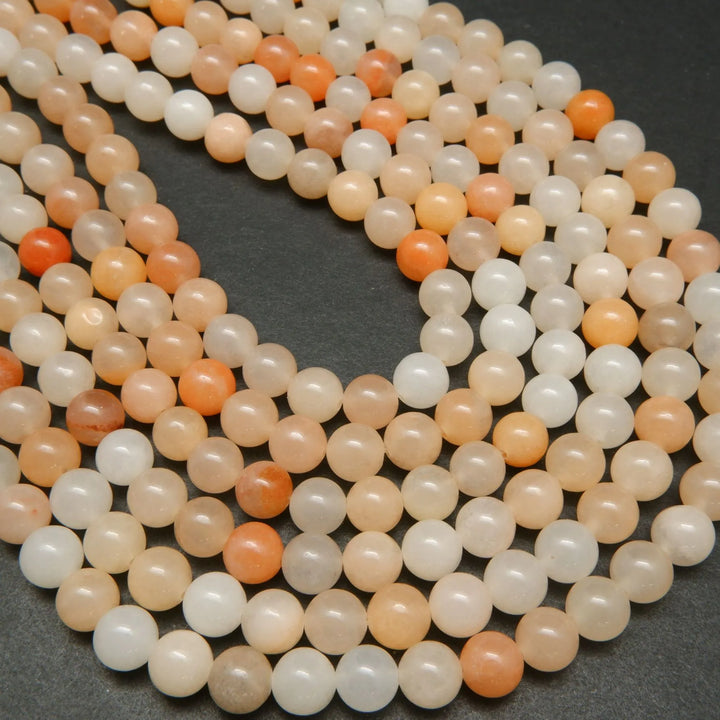Peach Aventurine Beads showing a mix of hues from light to dark peach, with an almost orange appearance.