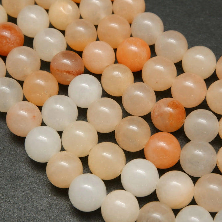 Peach Aventurine Beads showing a mix of hues from light to dark peach, with an almost orange appearance.