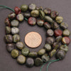Beads with a penny for size comparison on a gray background