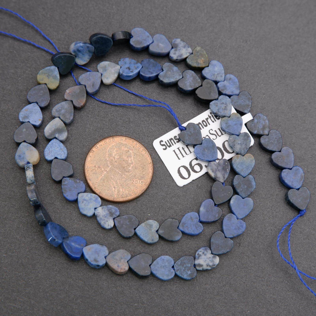 Heart-shaped beads on a string with a penny for scale on a gray background