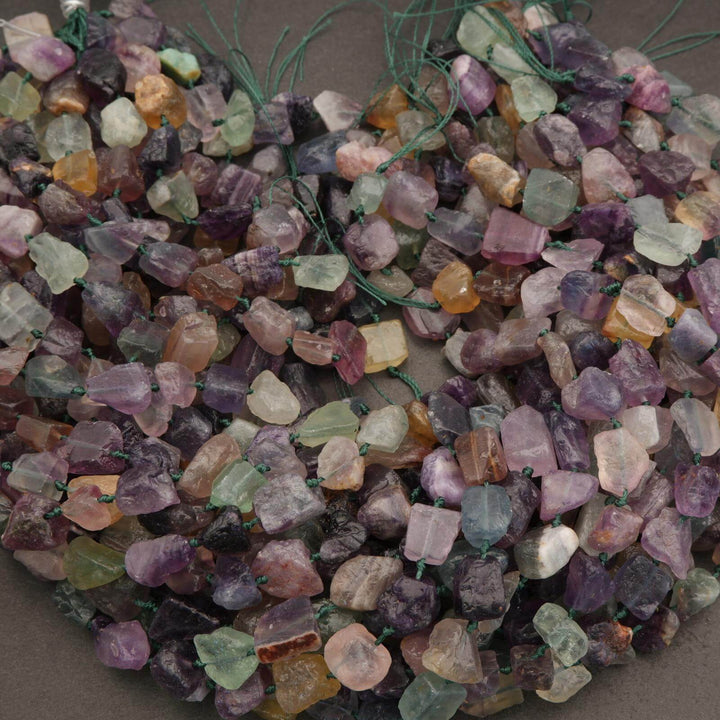 Close-up of multicolored gemstones on a string against a neutral background
