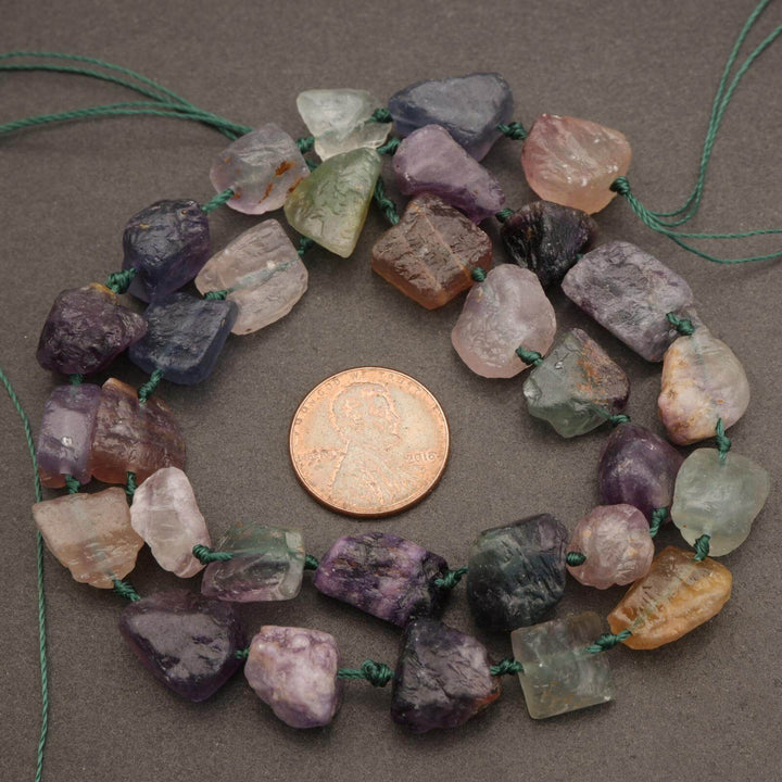 Necklace with multicolored stone beads and a penny for scale on a brown surface