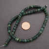 Green beaded necklace with a coin for scale on a gray background
