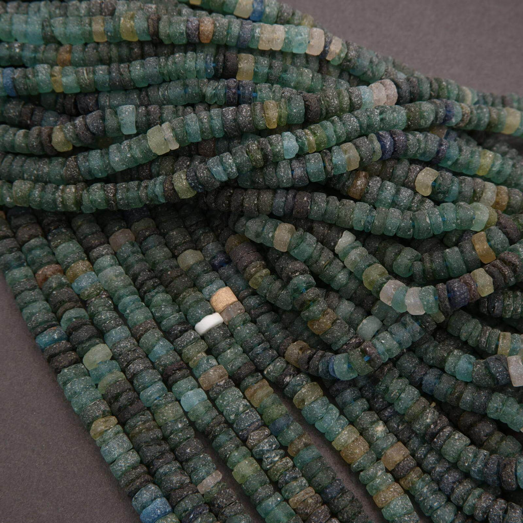 Close-up of a string of green and blue beads on a gray background