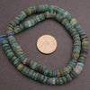 String of green and blue beads with a penny for scale on a gray background