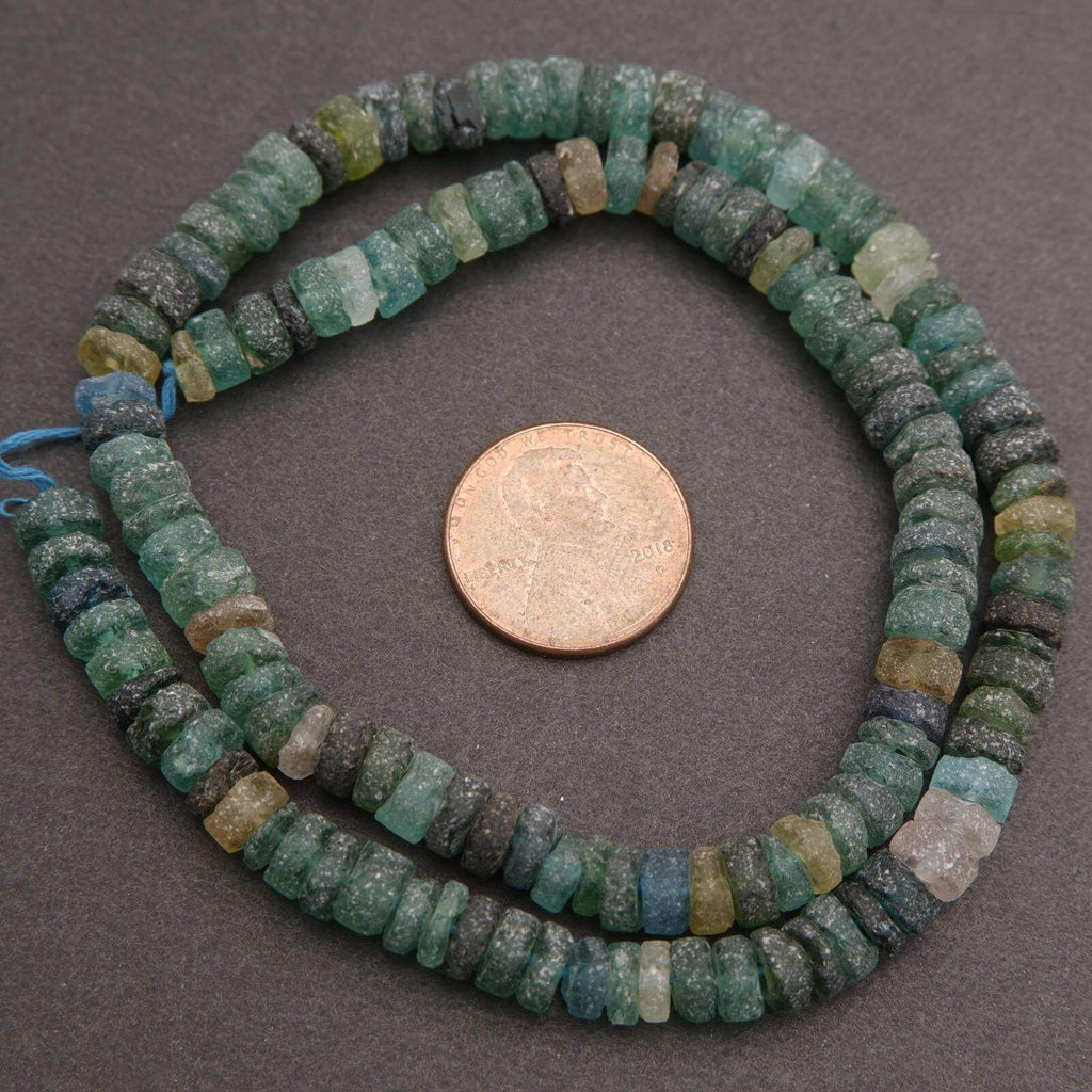 String of green and blue beads with a penny for scale on a gray background