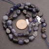 String of purple and gray beads with a penny for scale on a gray background