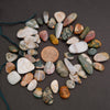 Assorted colorful stones arranged in a circular pattern on a dark surface with a penny in the center.