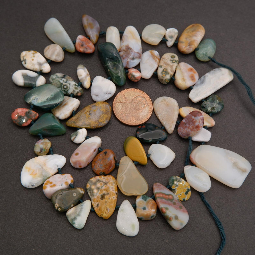 Assorted colorful stones on a dark surface with a penny for scale.