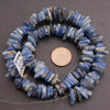 Blue stone beads on a gray background with a penny for scale