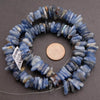 Blue stone beads on a gray background with a penny for scale