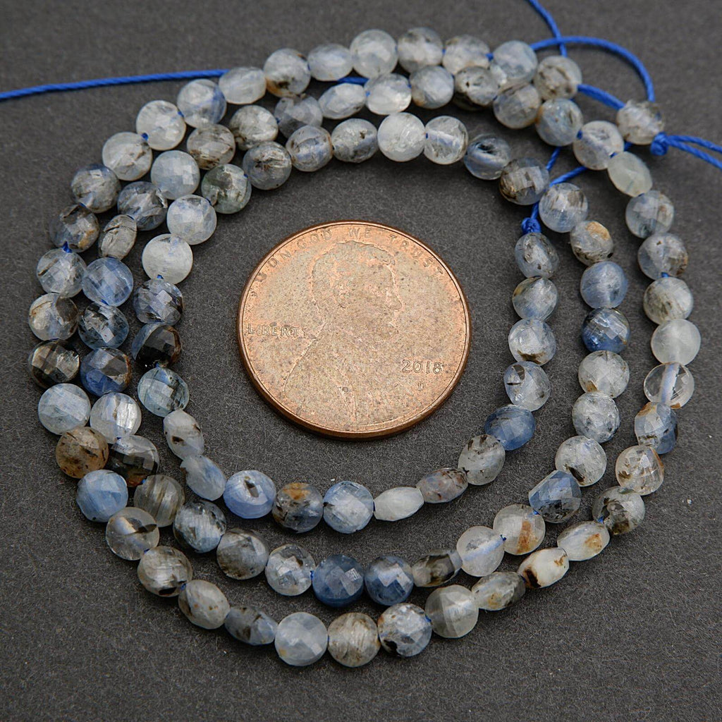 String of blue and gray beads with a penny for size comparison on a dark surface
