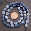 String of blue oval beads with a coin for size comparison on a gray background
