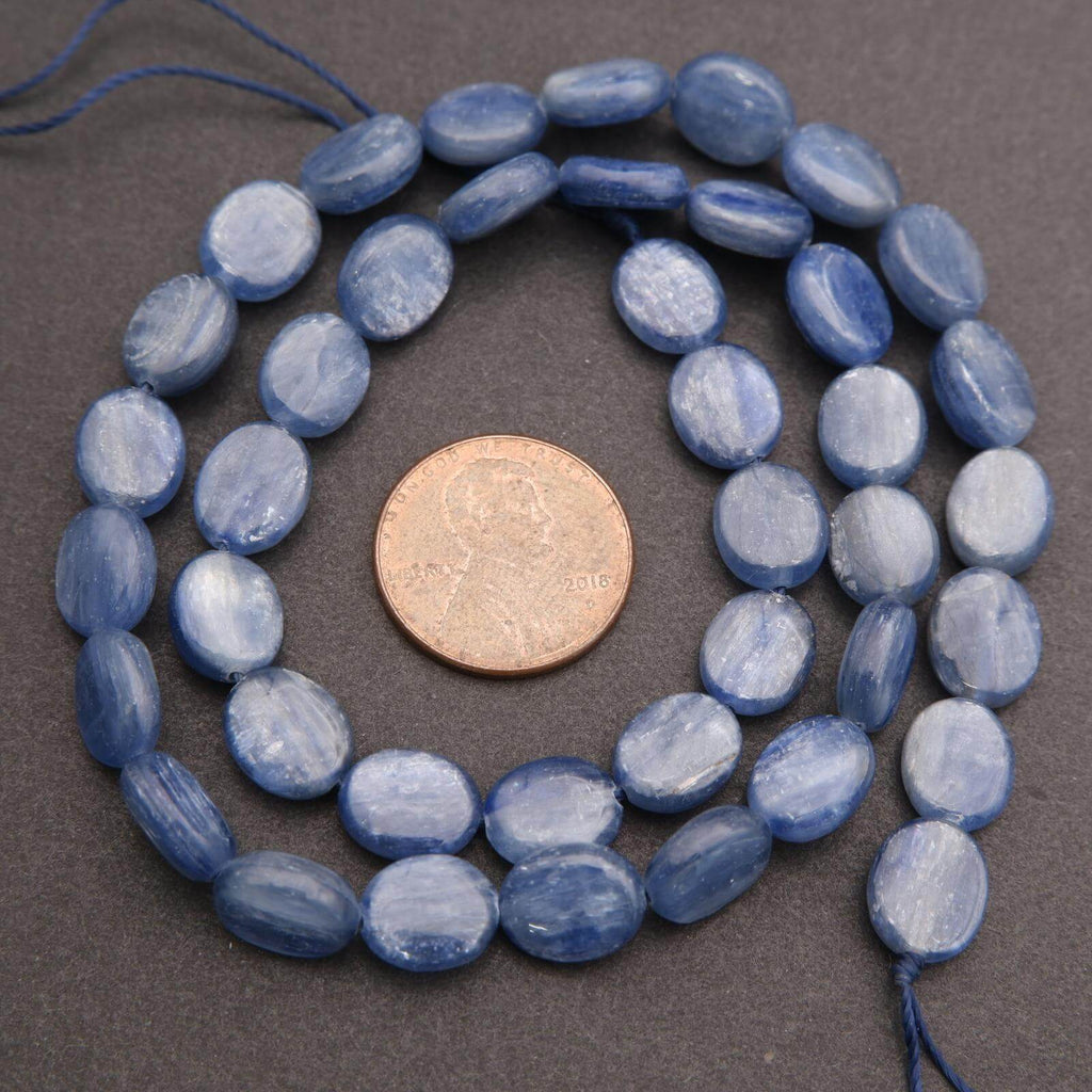String of blue oval beads with a coin for size comparison on a gray background