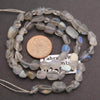 String of labradorite beads with a coin for scale on a dark background