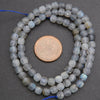 String of faceted beads with a coin for scale on a gray background