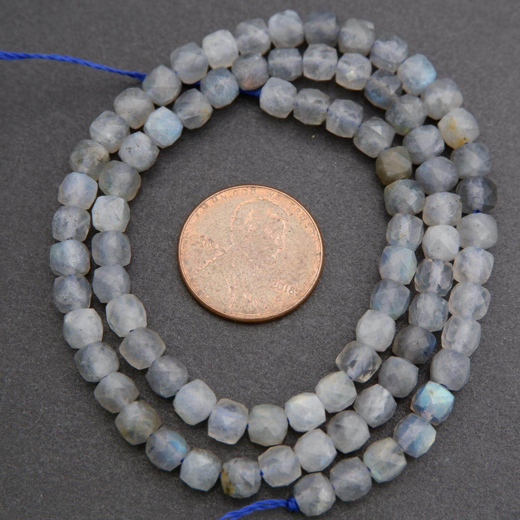 String of faceted beads with a coin for scale on a gray background