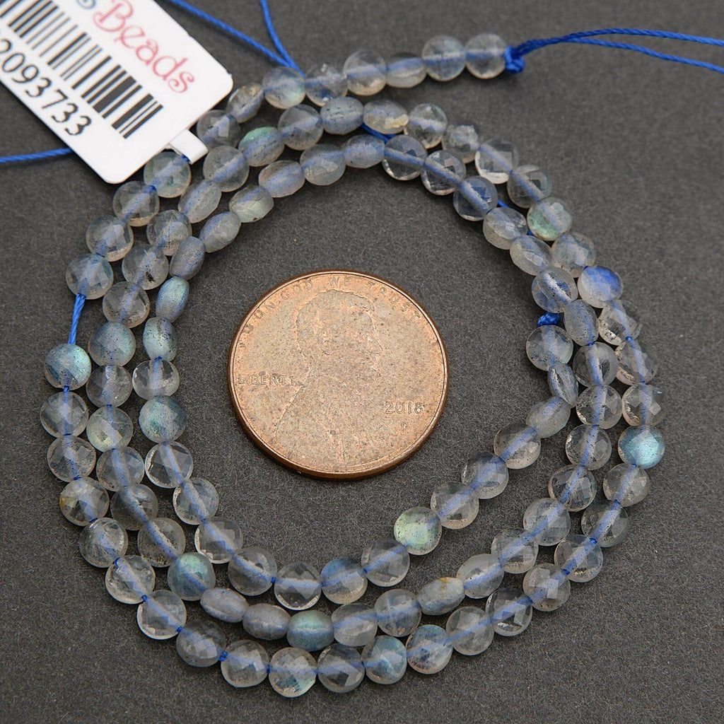 String of small beads with a penny for scale on a gray surface