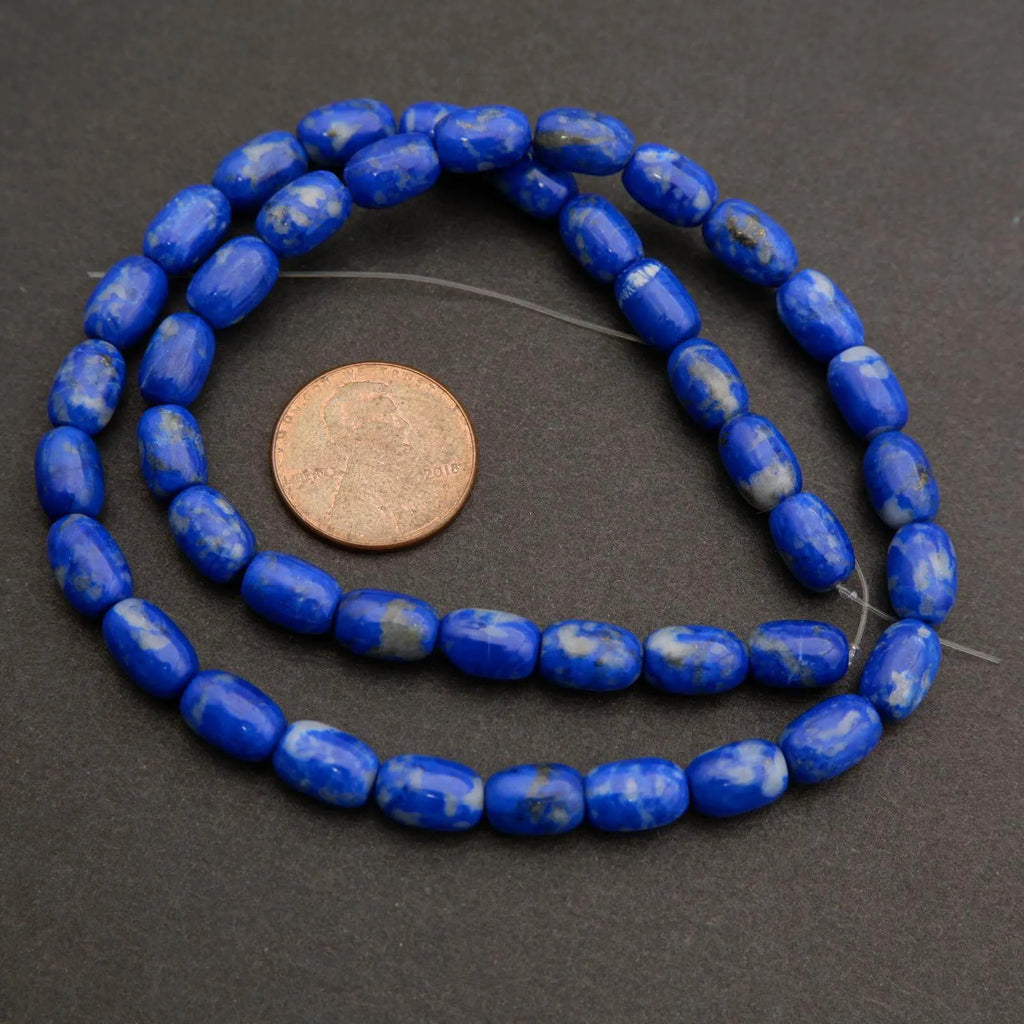 Blue beads on a string with a coin for size comparison on a dark background