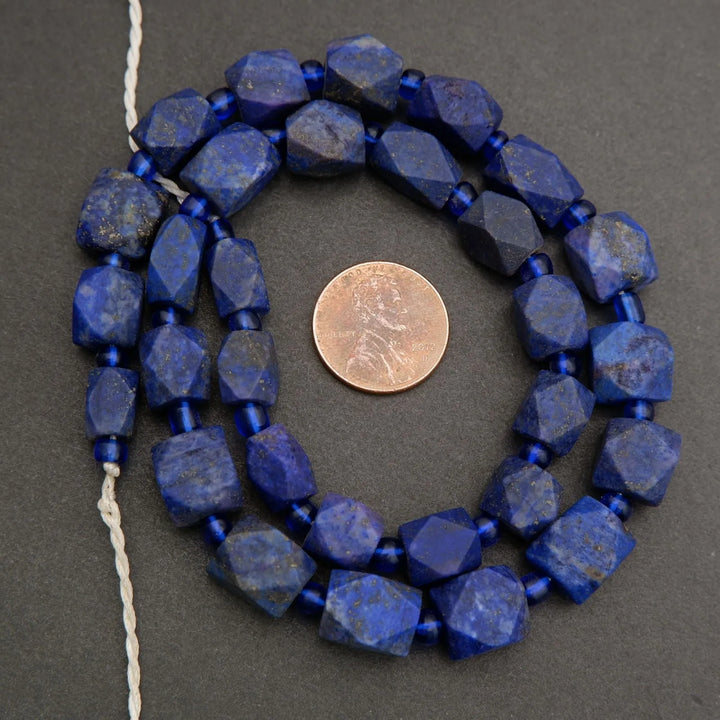 String of blue beads with a penny for size comparison on a gray background
