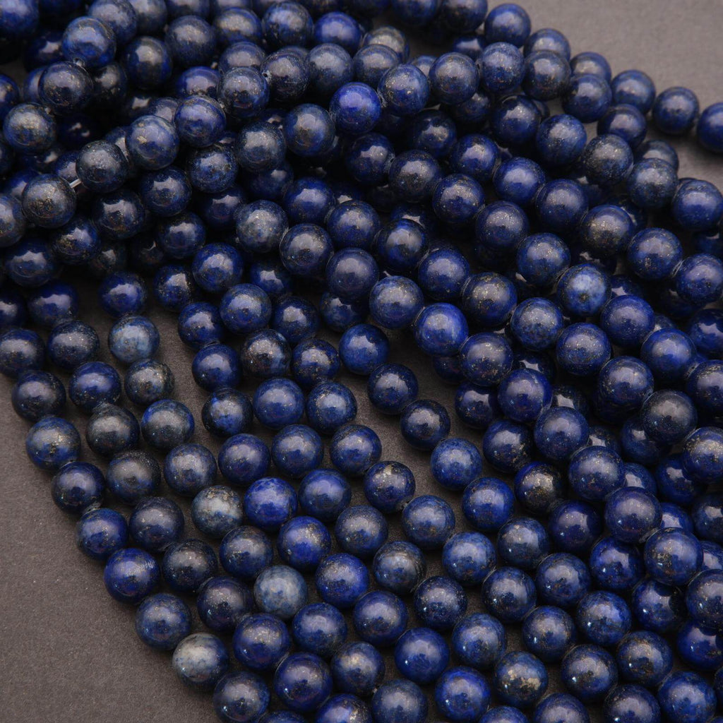 Grouped strands of polished lapis lazuli beads on a flat surface.