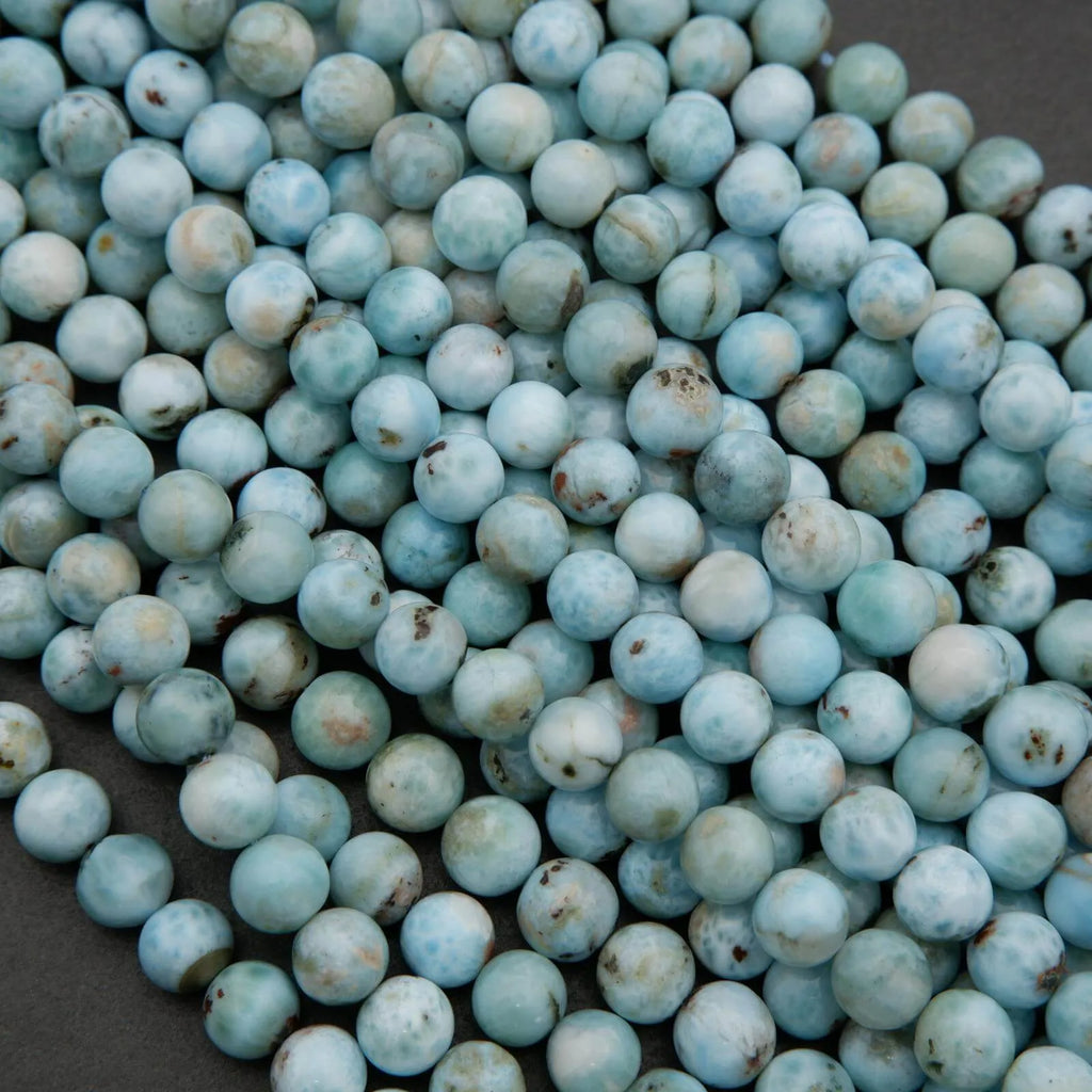 Strands of Larimar beads featuring pale blue ocean-like swirls and natural inclusions