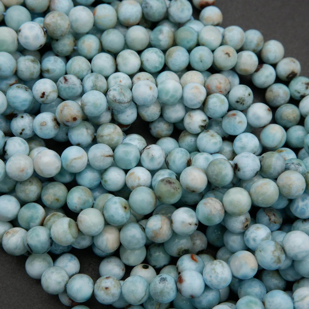 Round Larimar beads with light blue, white, and subtle brown mineral markings